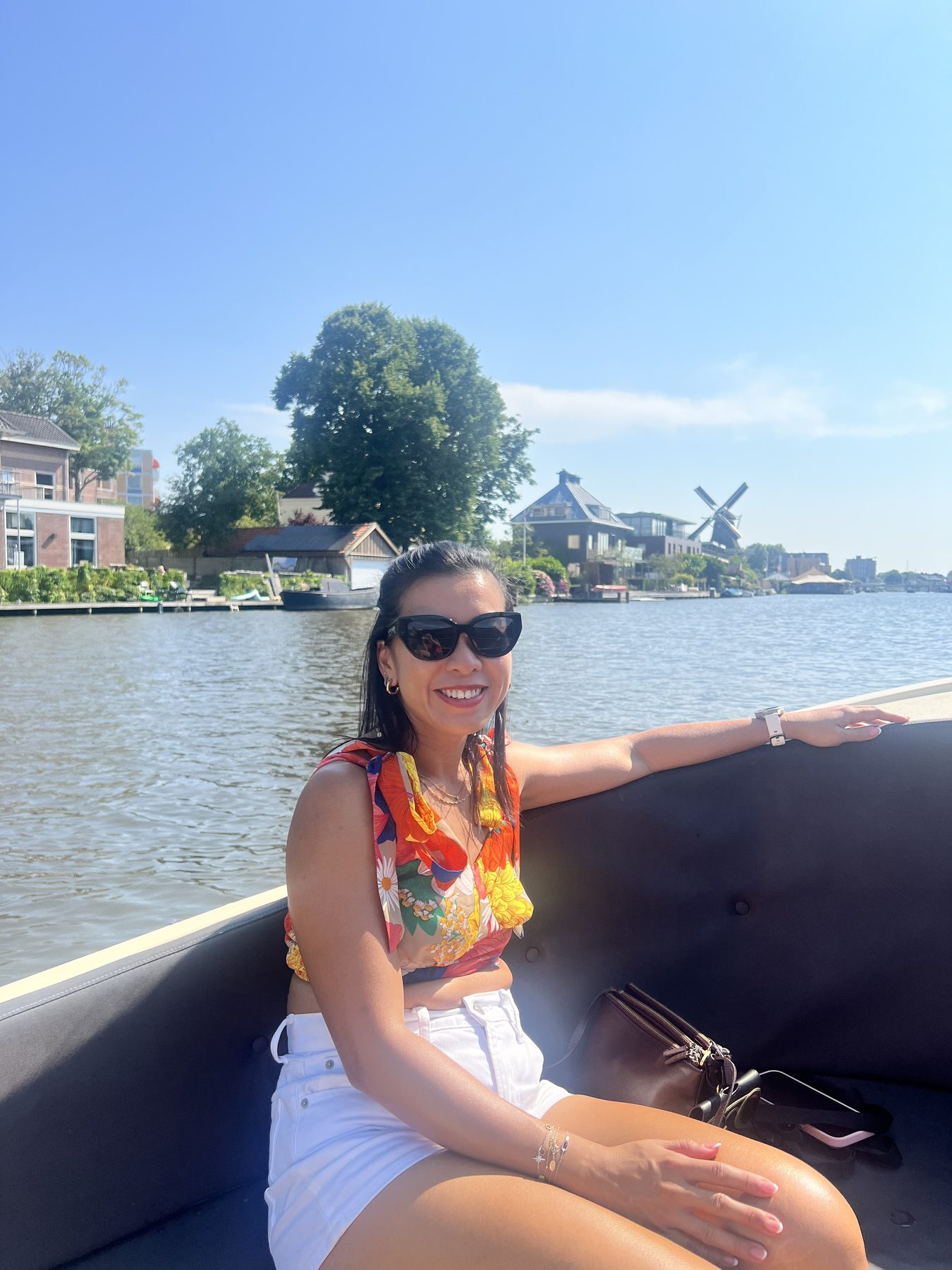 Cristyne living her best canal life—floral top, big smile, mill on the far bank doing the Dutch backdrop job.